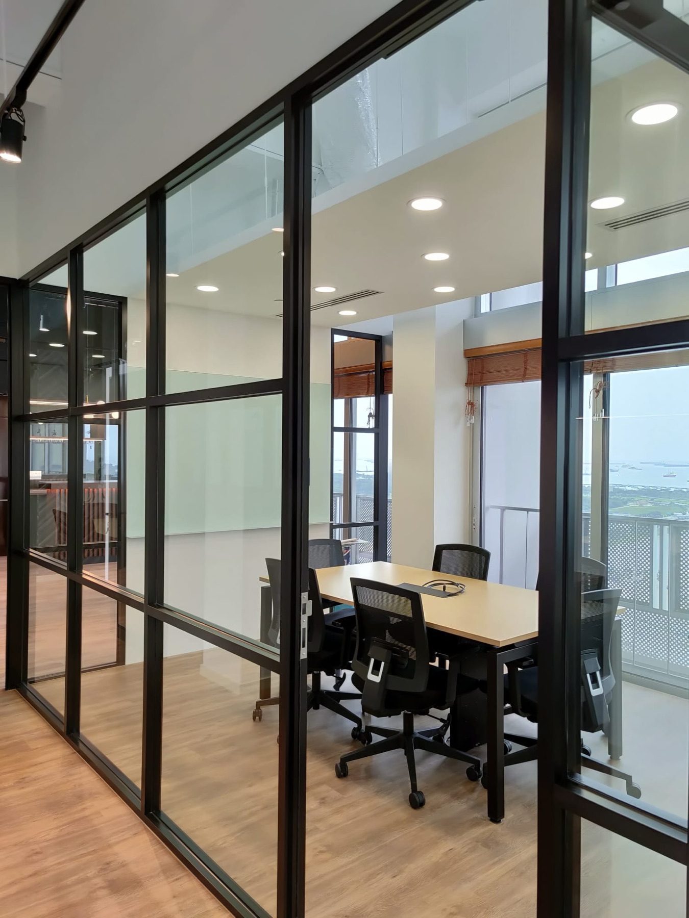 Glass-walled meeting room with black frames and timber floor, Eon Shenton
