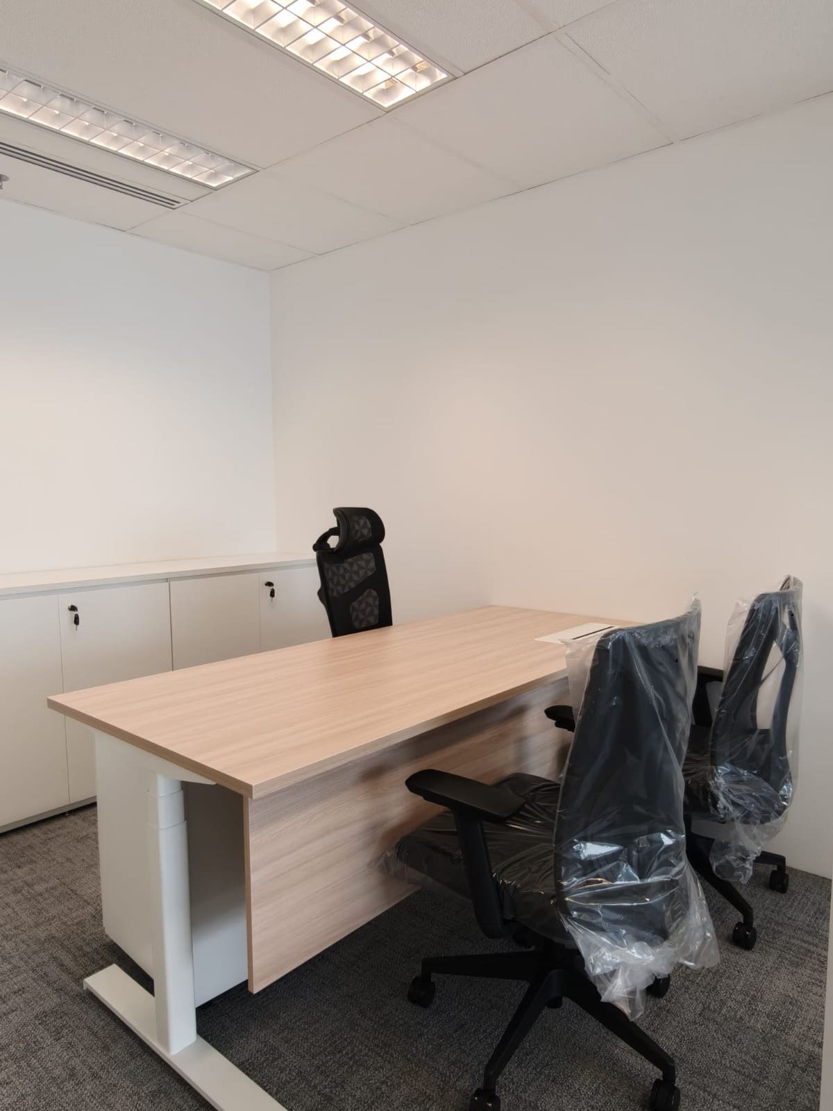 Director room with a timber desk, chairs still wrapped at handover, OUE Downtown 1, office by Metadesign Interior