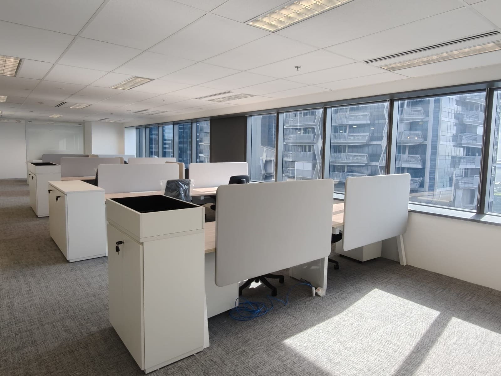 Open-plan workstations in morning light with city towers outside, OUE Downtown 1, office by Metadesign Interior