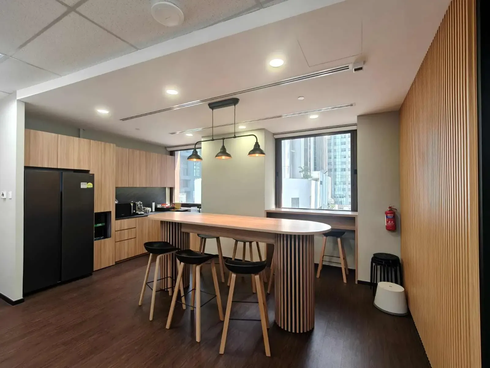 Office pantry with custom timber carpentry and island counter, part of an office fit-out in Singapore