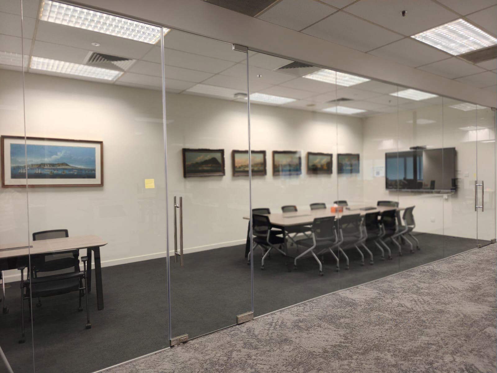 Glass-walled meeting room with a wall screen and long table, New Tech Park