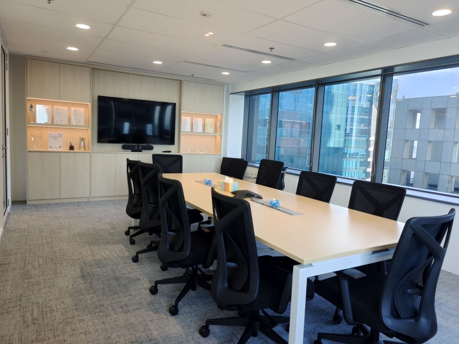 Boardroom with oak table and built-in cabinet wall with lit niches, designed and built by Metadesign Interior at OUE Downtown 1