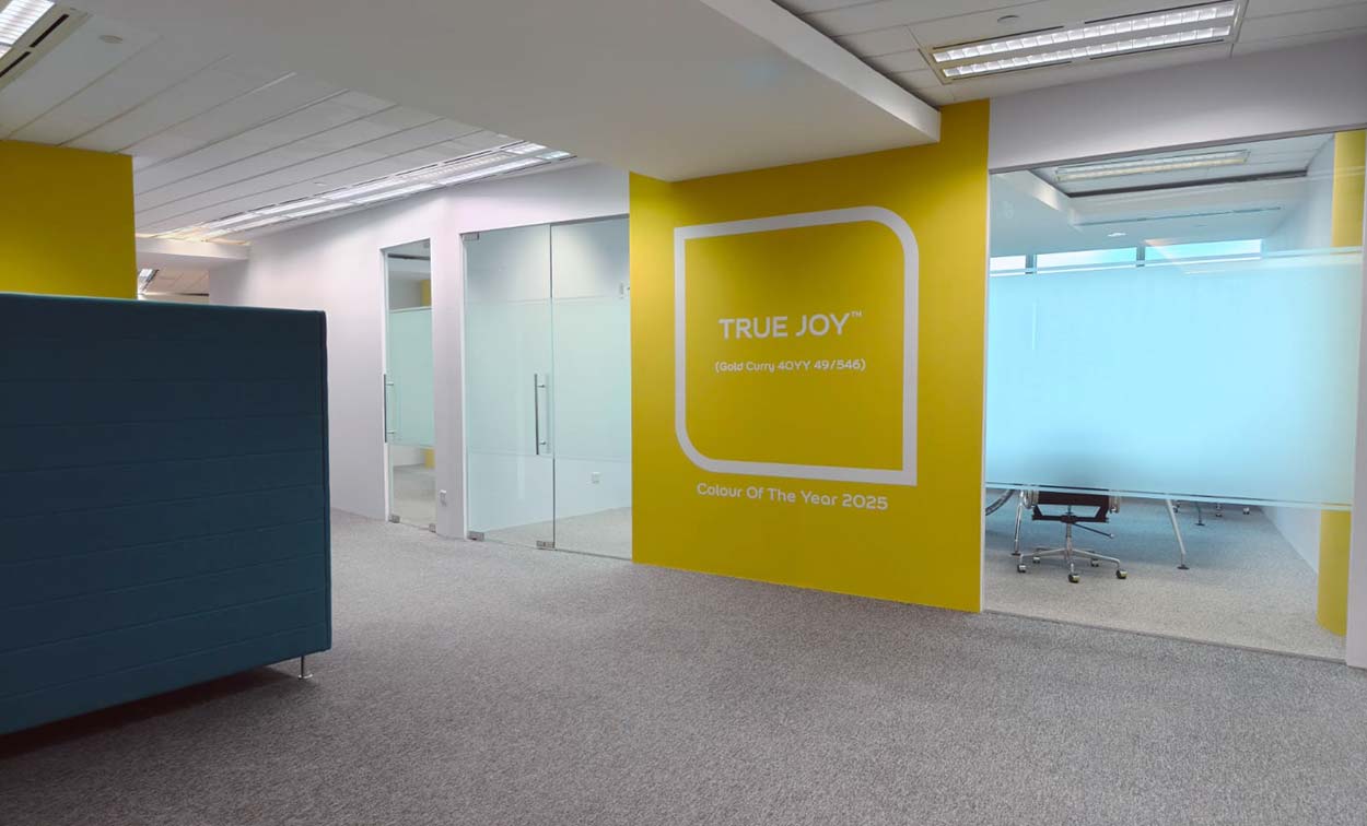 Yellow feature wall between glass-partitioned rooms. The Signature, AkzoNobel office.