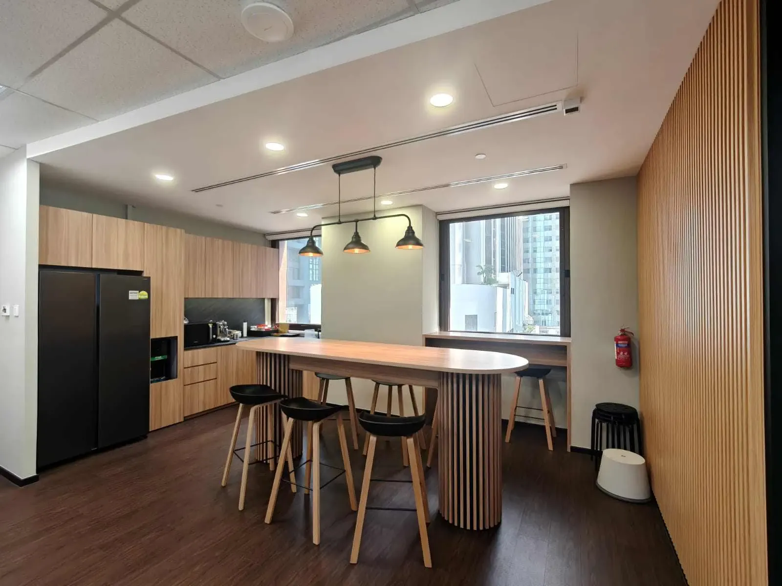 Office pantry with custom timber carpentry and island counter, part of an office fit-out in Singapore