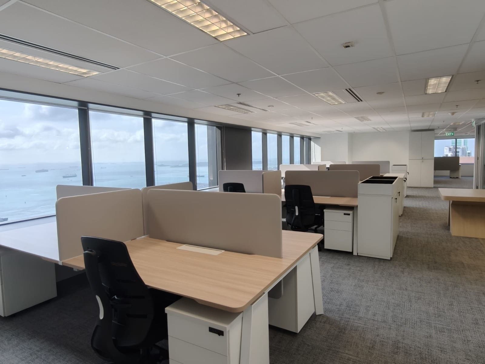 Sunlit open-plan workstations with oak-top desks and sea views, OUE Downtown 1