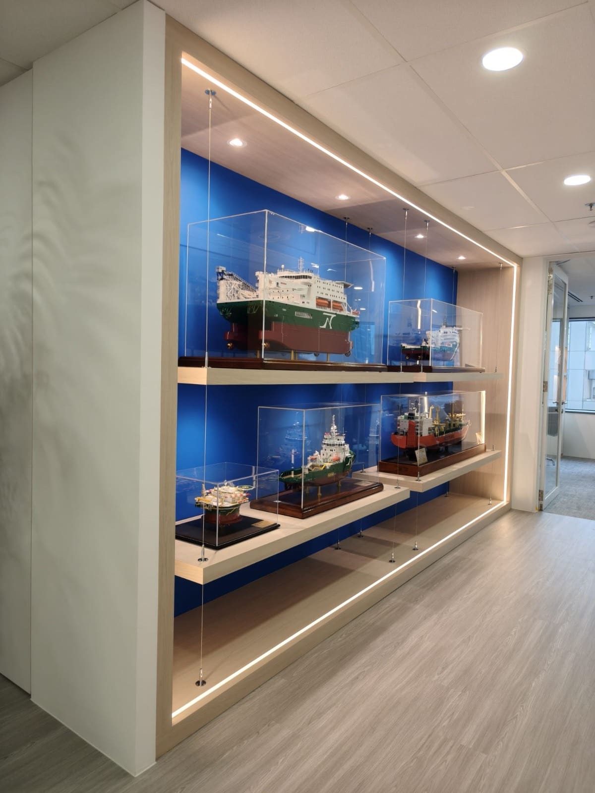 Lit display wall with glass shelves and a blue back panel, OUE Downtown 1, office by Metadesign Interior
